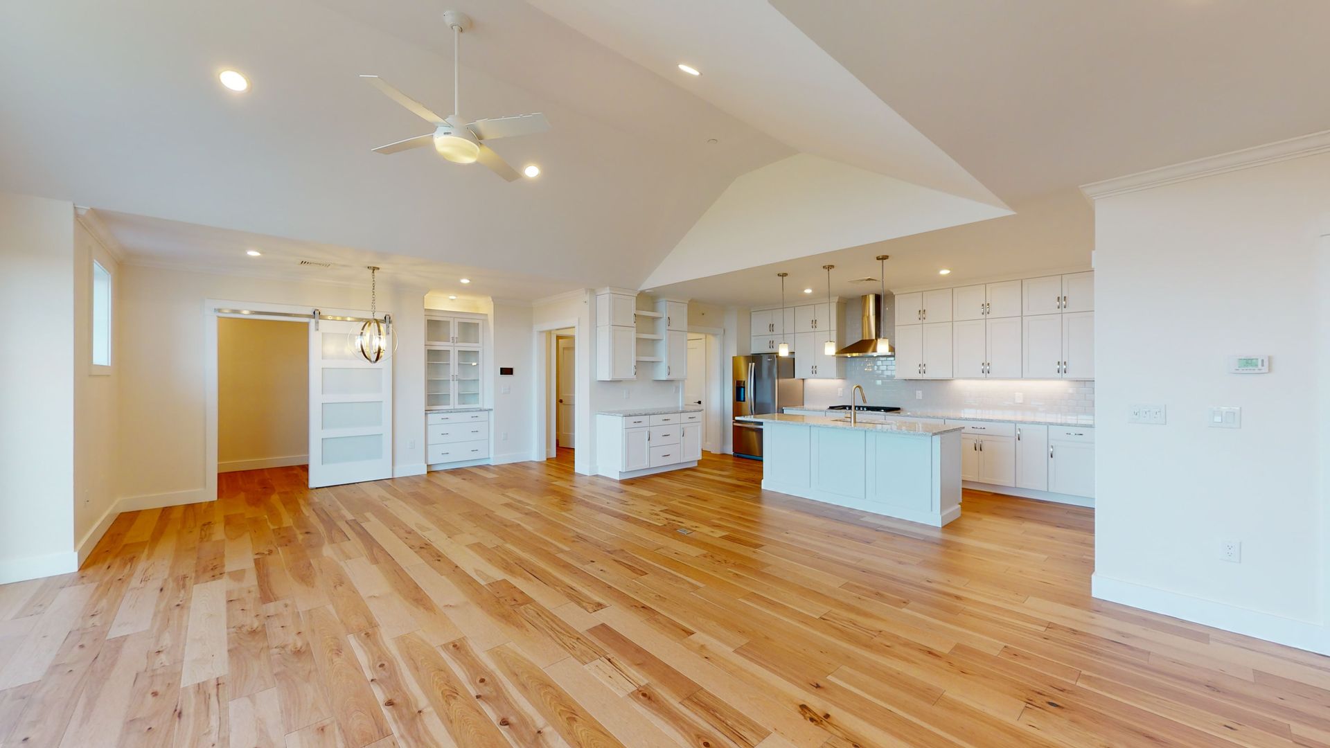 A living room with hardwood floors and a kitchen in a house.