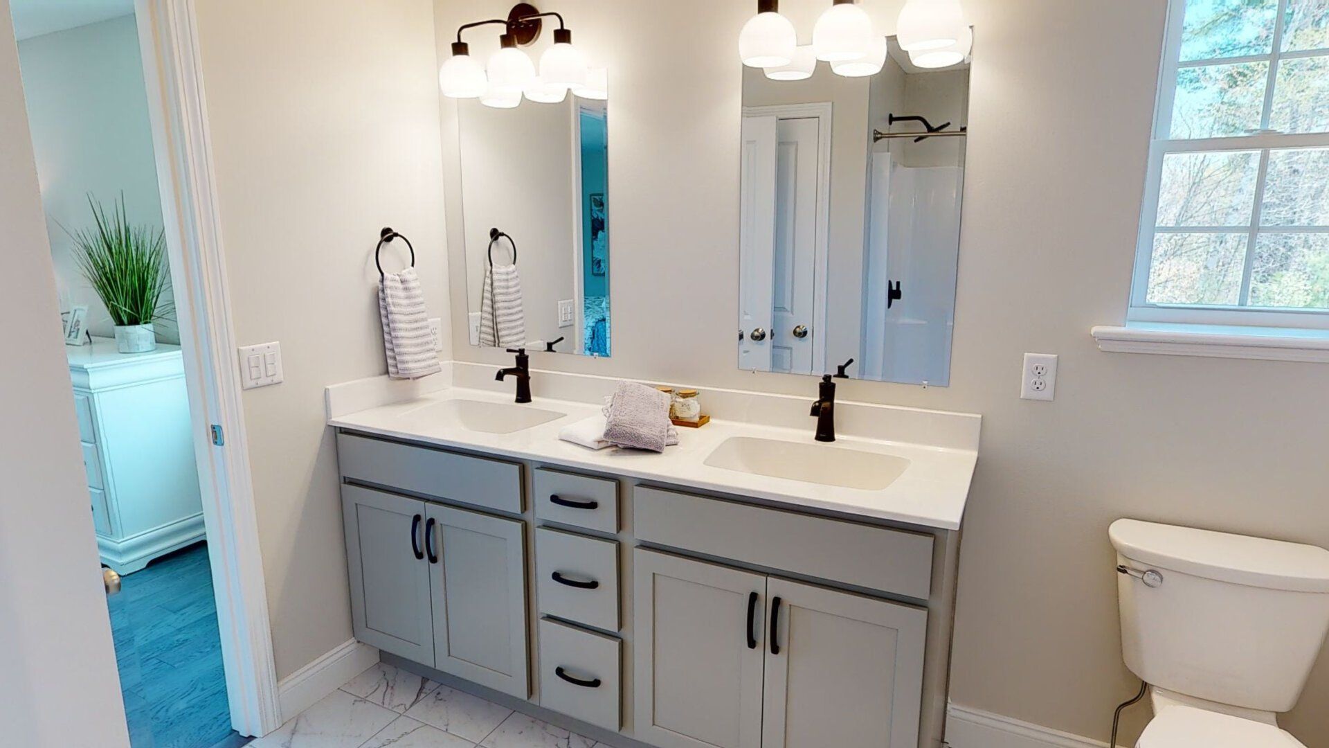 A bathroom with two sinks , a toilet and two mirrors.