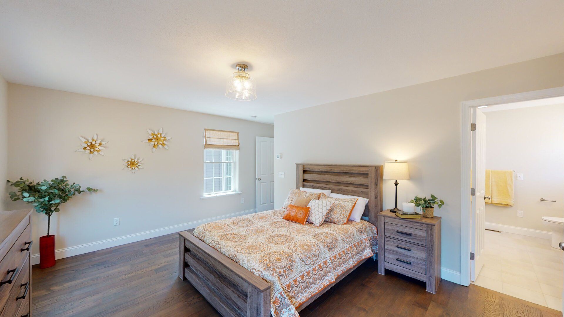 A bedroom with a bed , nightstand , dresser and window.