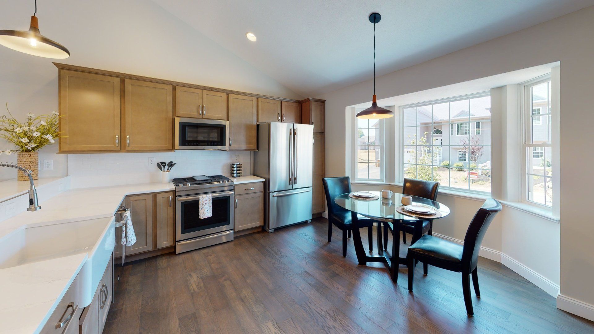 A kitchen with wooden cabinets , stainless steel appliances , a table and chairs.