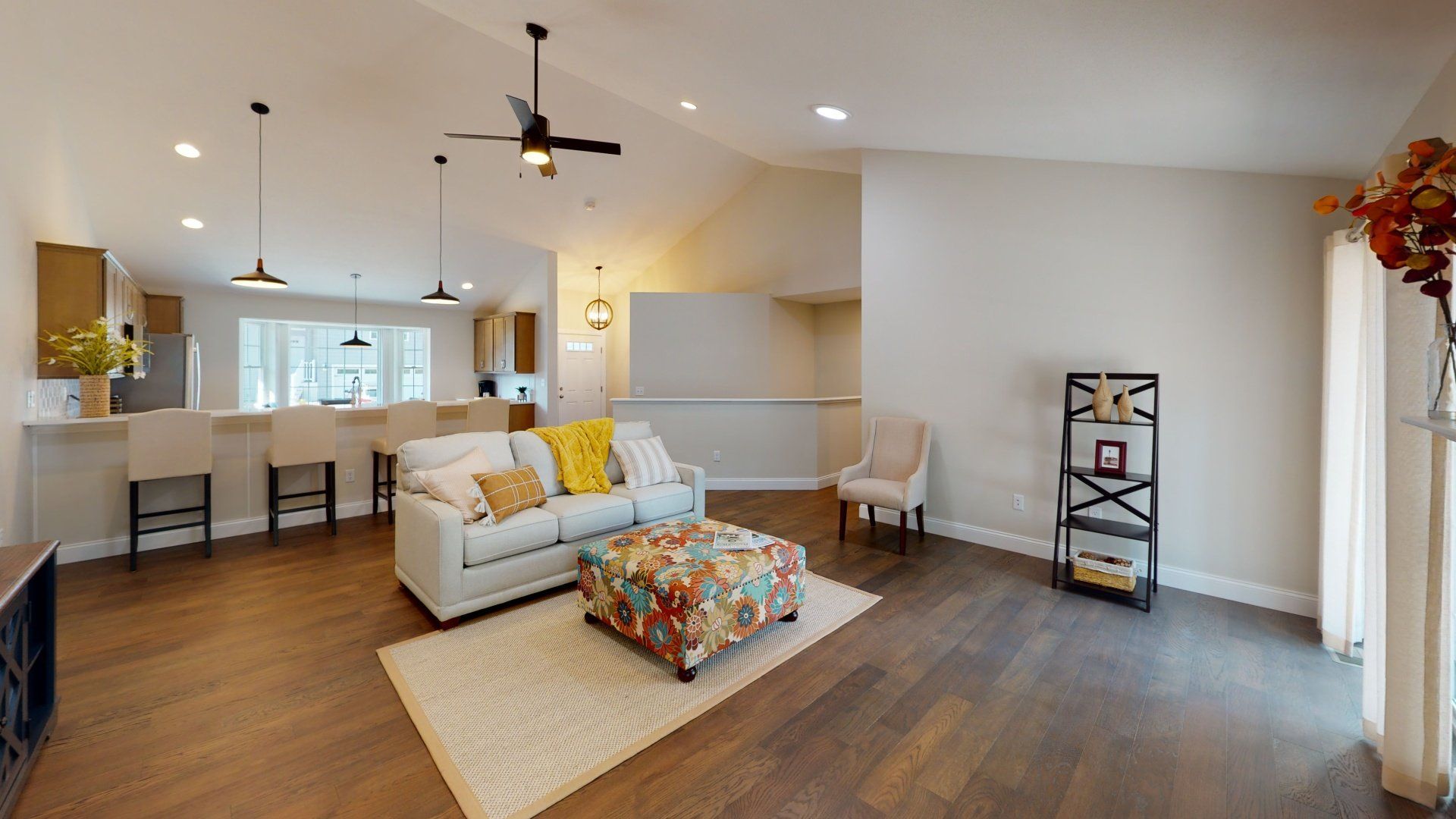 A living room with a couch , chairs , ottoman and ceiling fan.