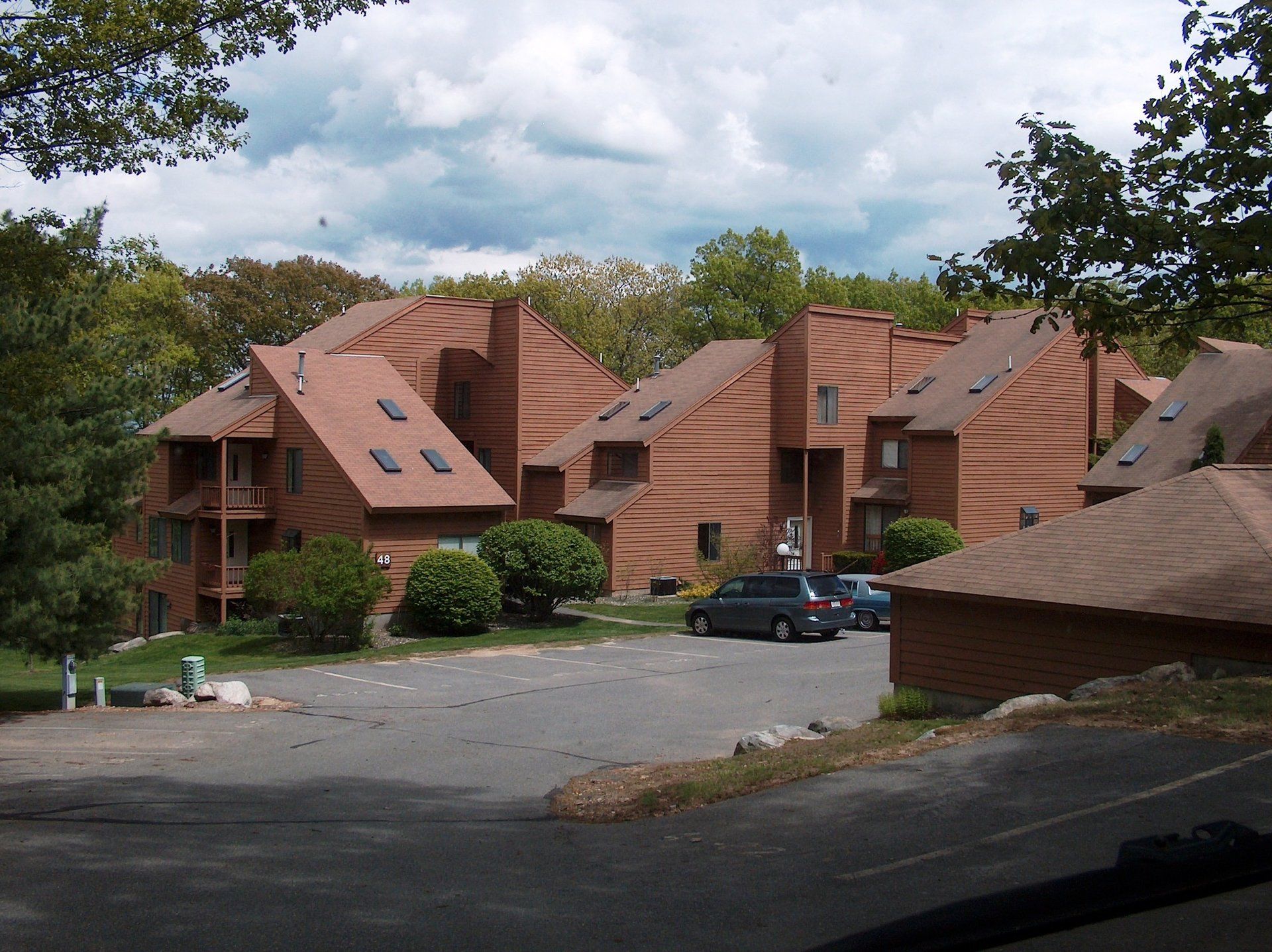 A row of apartment buildings with a parking lot in front of them