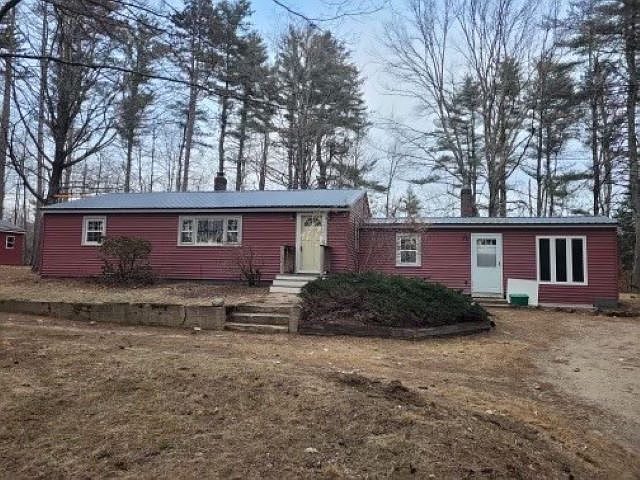 A red house with a metal roof is surrounded by trees.