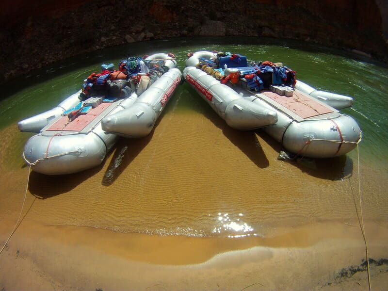 Two rafts are sitting on the shore of a body of water