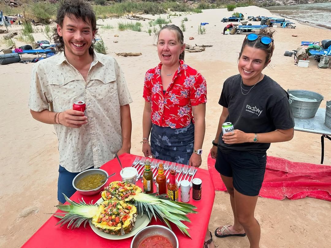 A group of people are standing around a table with food on it.