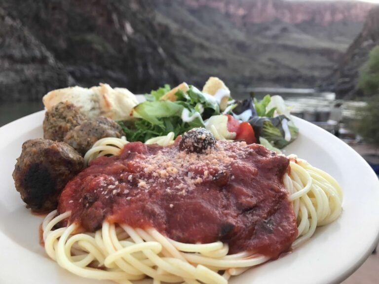 A white plate topped with spaghetti meatballs and a salad