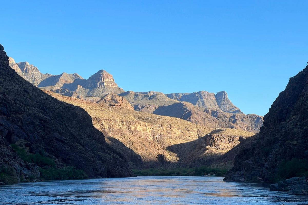 A river runs through a canyon with mountains in the background.