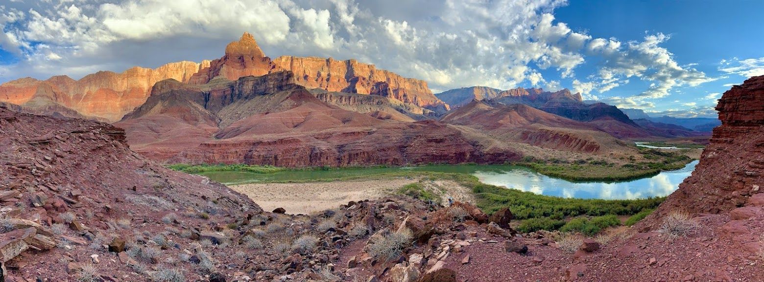 A river runs through a desert landscape with mountains in the background.