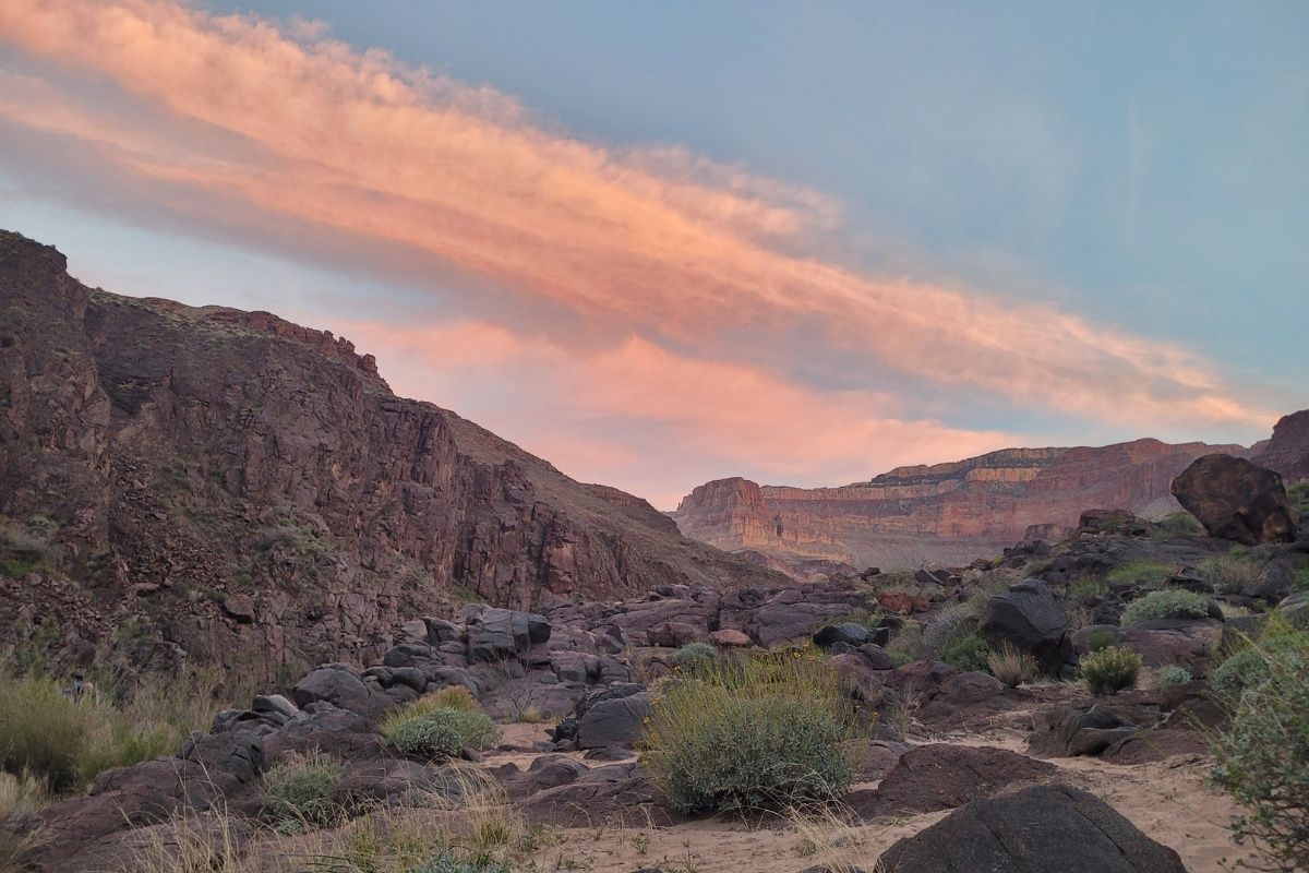 A sunset over a rocky desert landscape with mountains in the background.