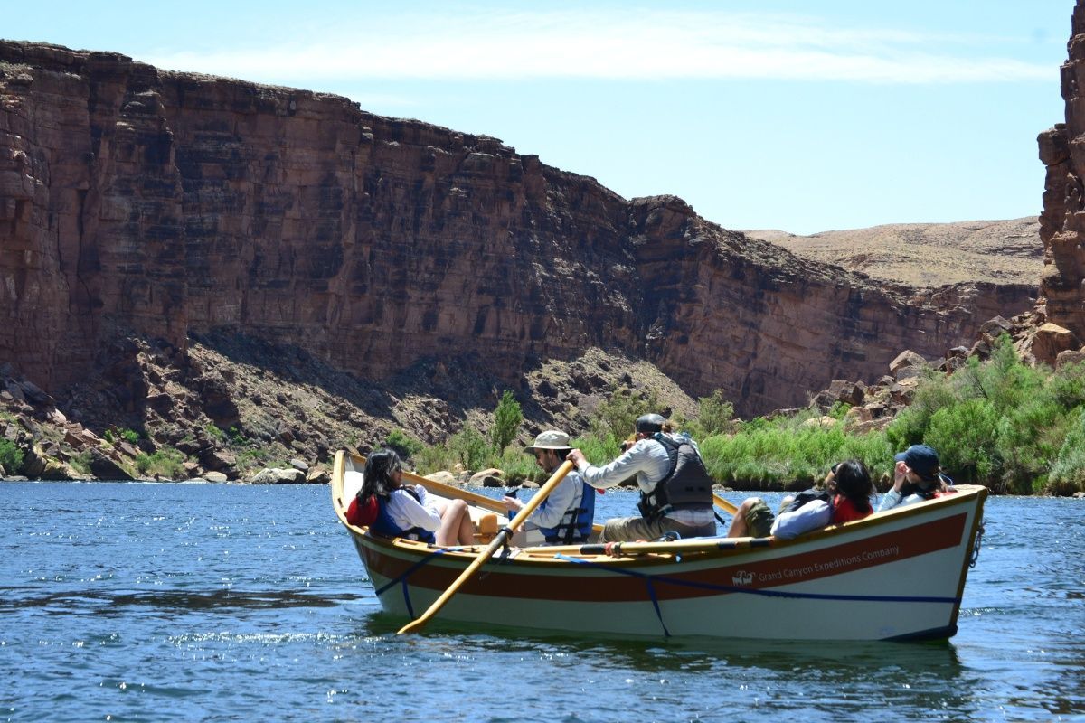 A group of people are rowing a boat down a river