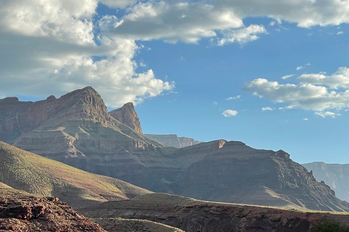 A mountain range with a blue sky and clouds in the background