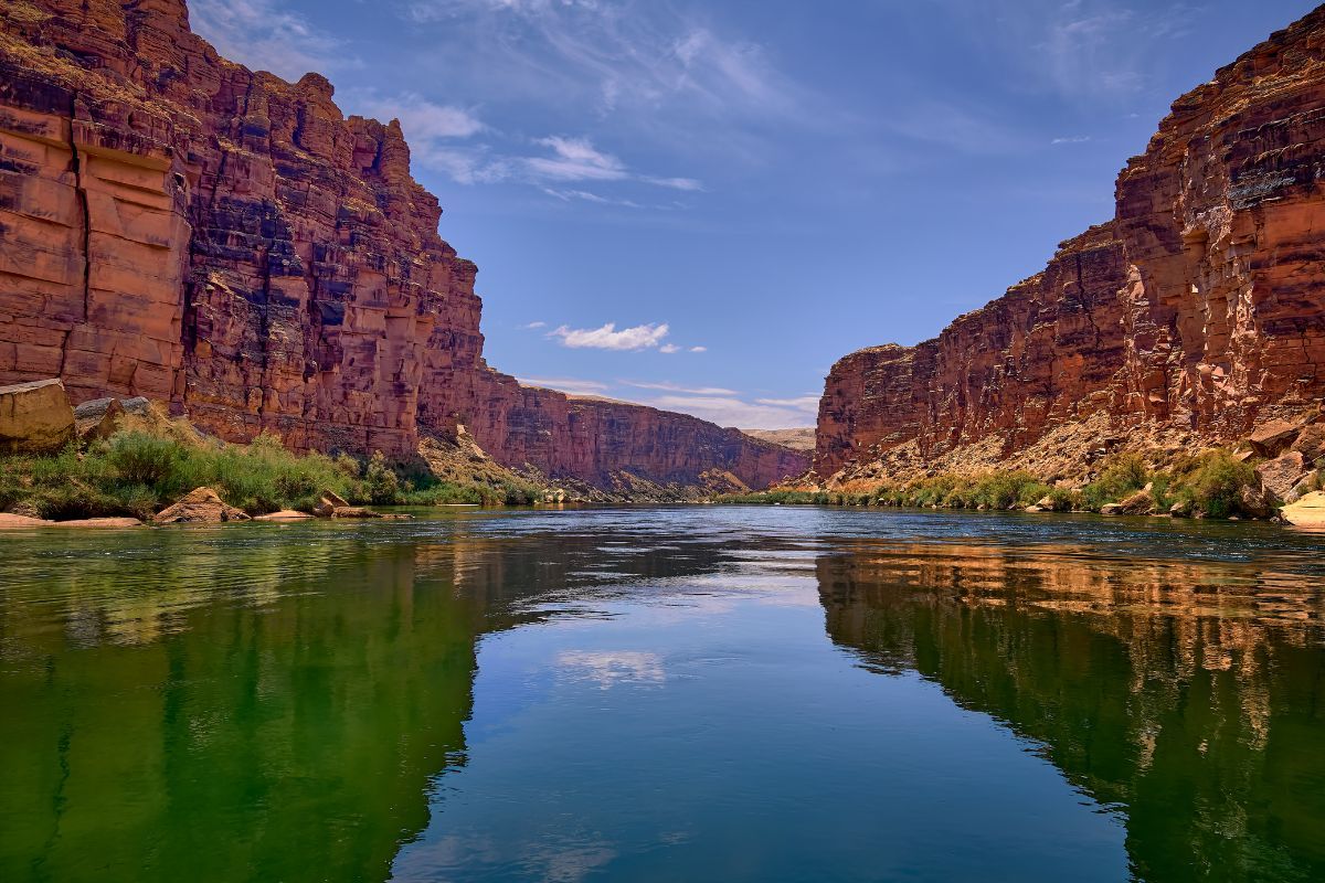 River flowing between red rock canyon walls under a blue sky.