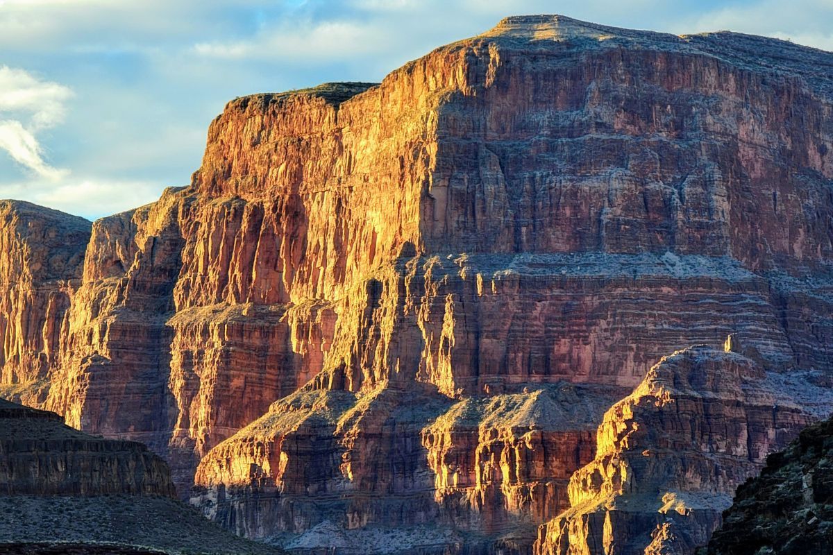 Sunlit, layered red-brown canyon walls under a blue sky.