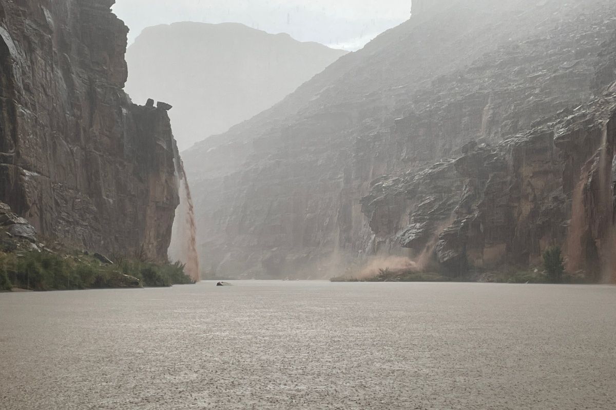 A river in the middle of a canyon with mountains in the background.