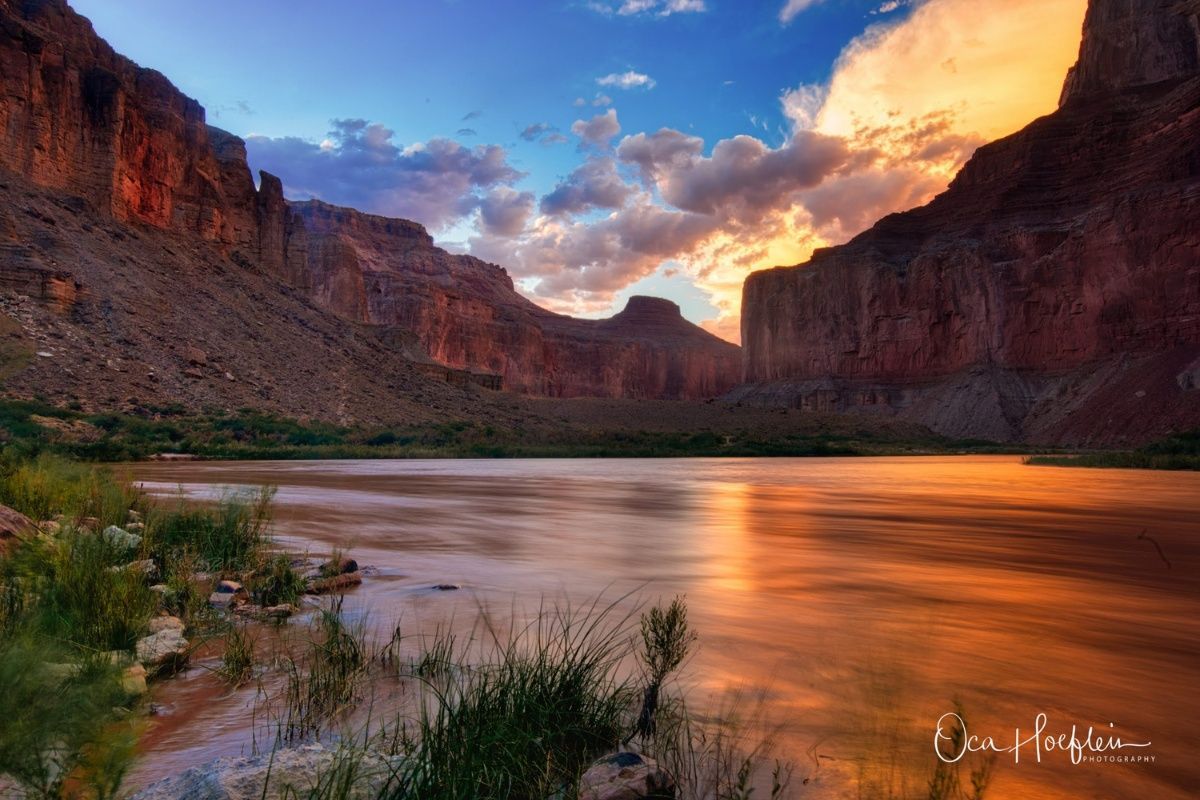 A river flowing through a canyon with mountains in the background at sunset.