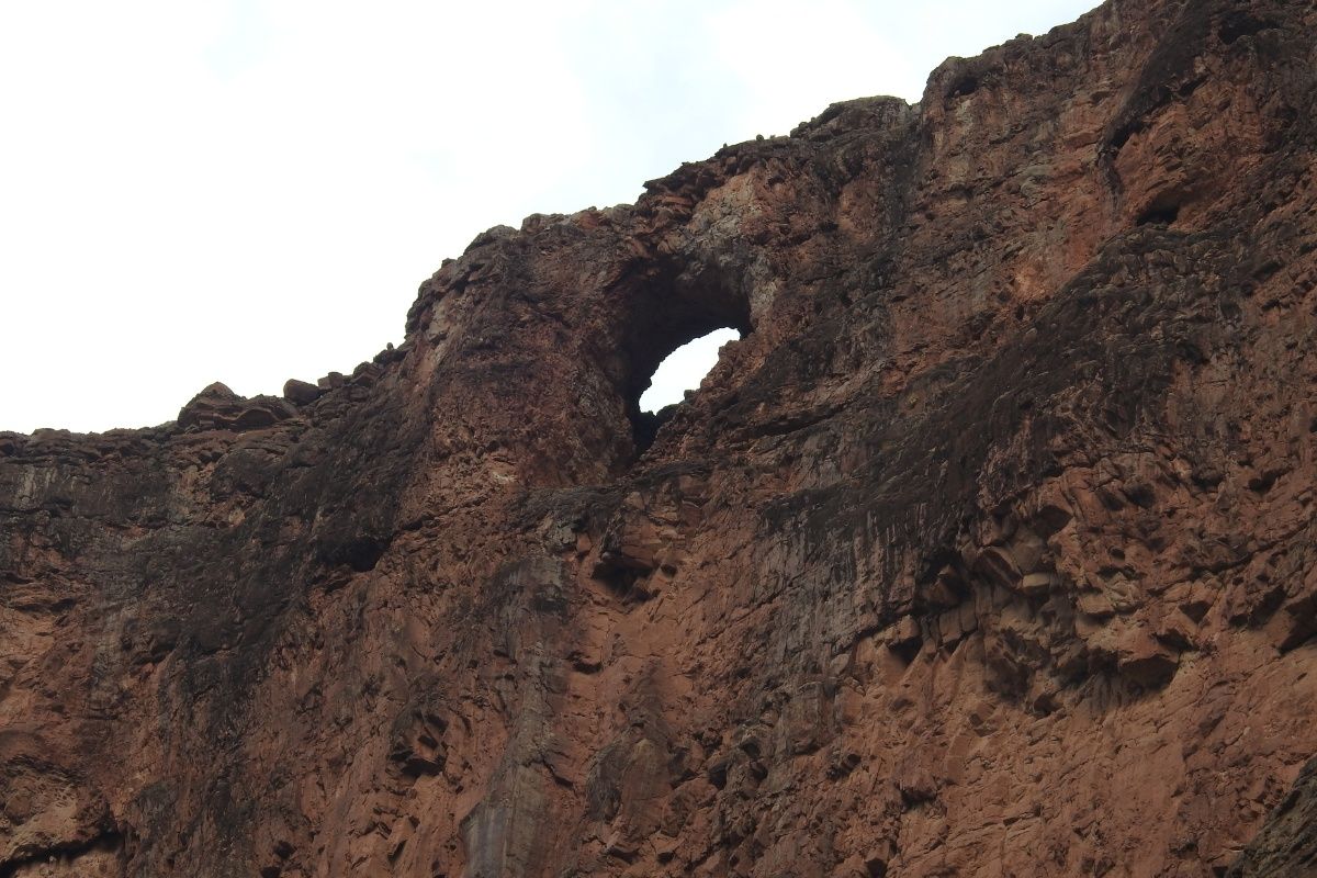 A rocky cliff with a hole in the middle of it