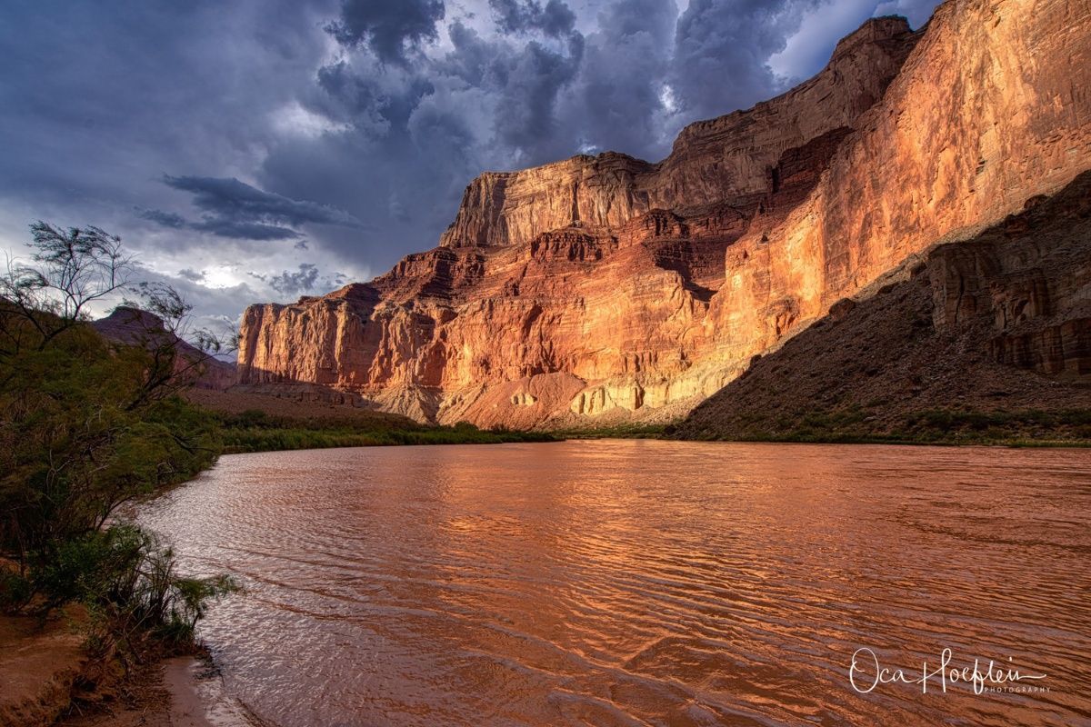 A river flowing through a canyon with a mountain in the background.