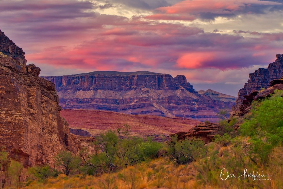 A sunset over a canyon with a mountain in the background.