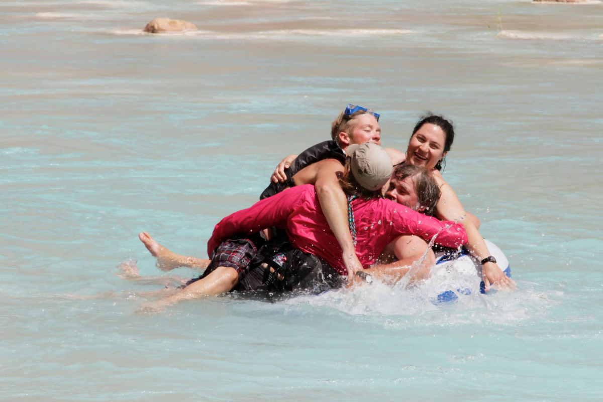 A group of people are laying on top of each other in the water