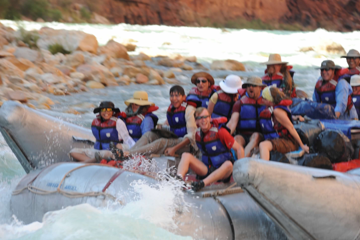 A group of people in life jackets are rafting down a river