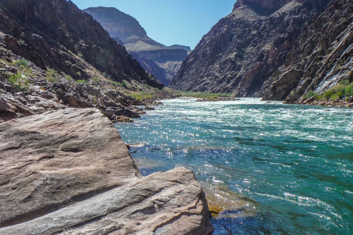 A river flowing through a canyon with mountains in the background