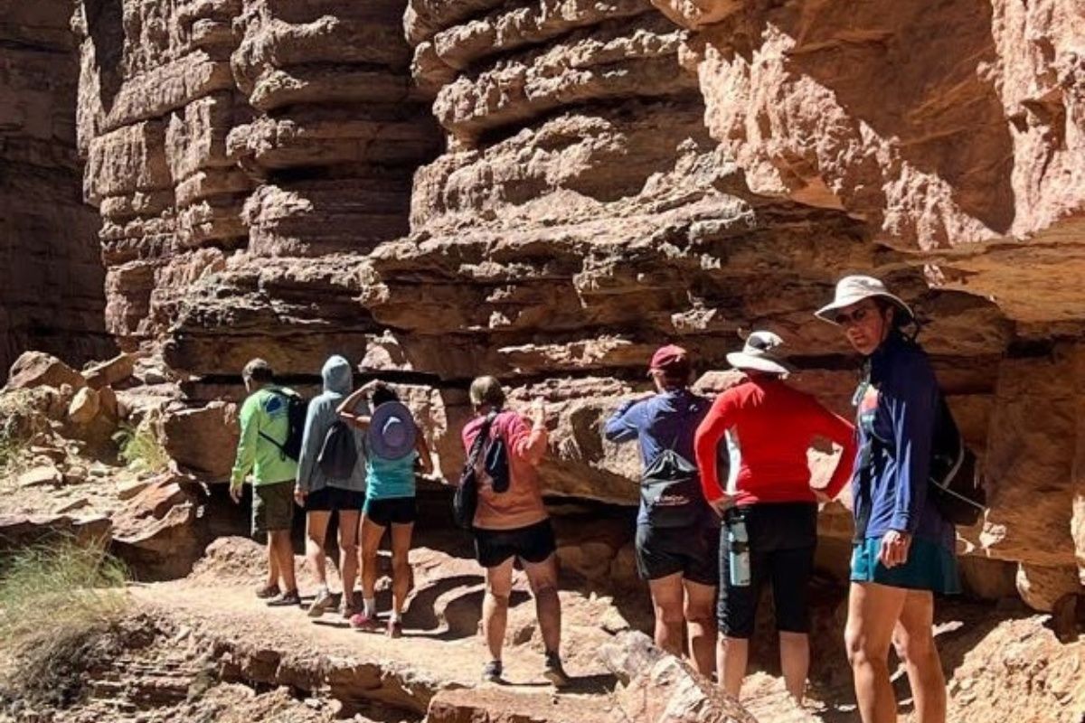 A group of people are standing in front of a rock wall.