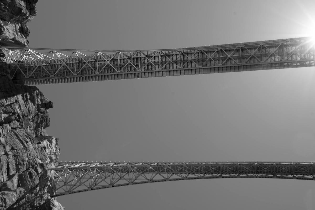 A black and white photo of a bridge over a river.