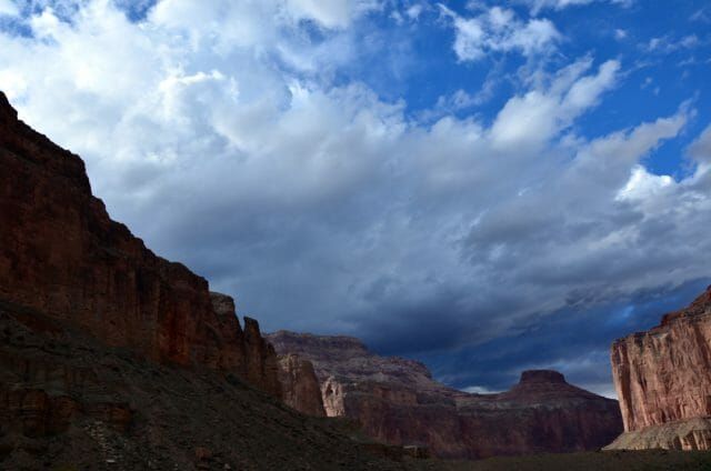 A cloudy sky over a canyon with mountains in the background