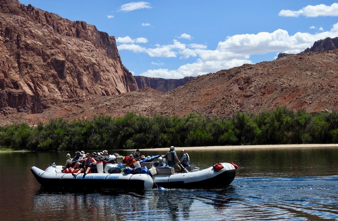 Two rafts are floating on a river with mountains in the background.
