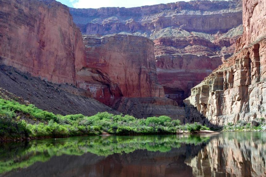 A river in the middle of a canyon with mountains in the background.