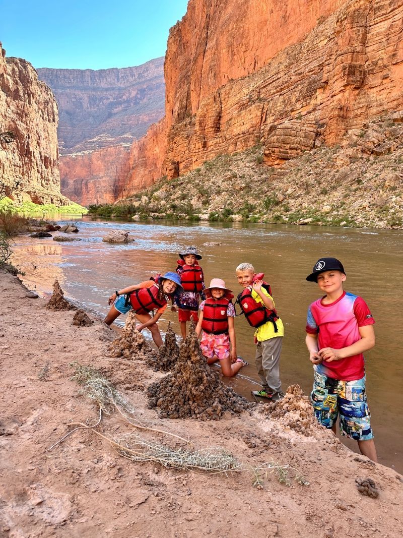 A group of children are standing next to a river.