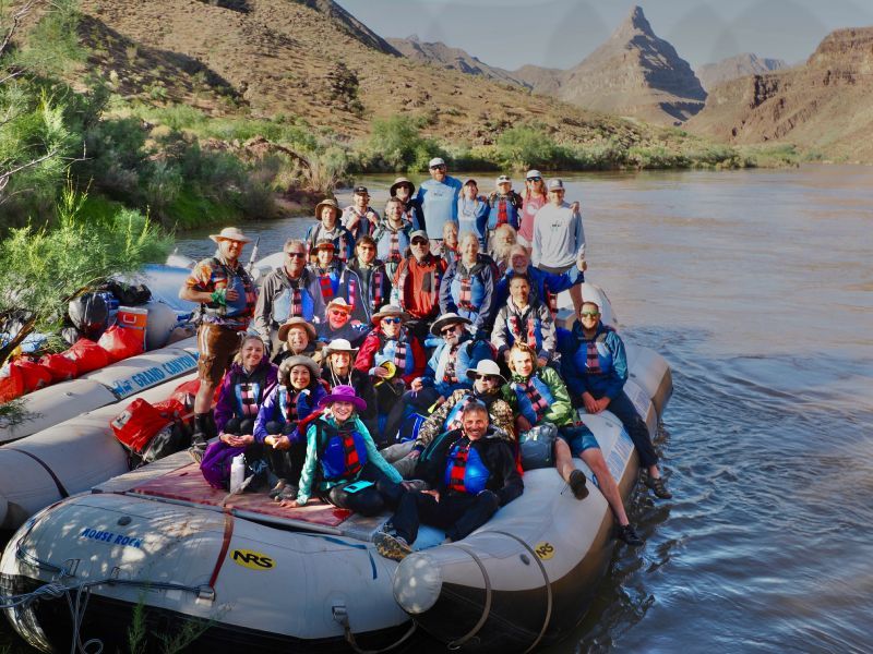 A group of people are sitting on a raft that says raft on it