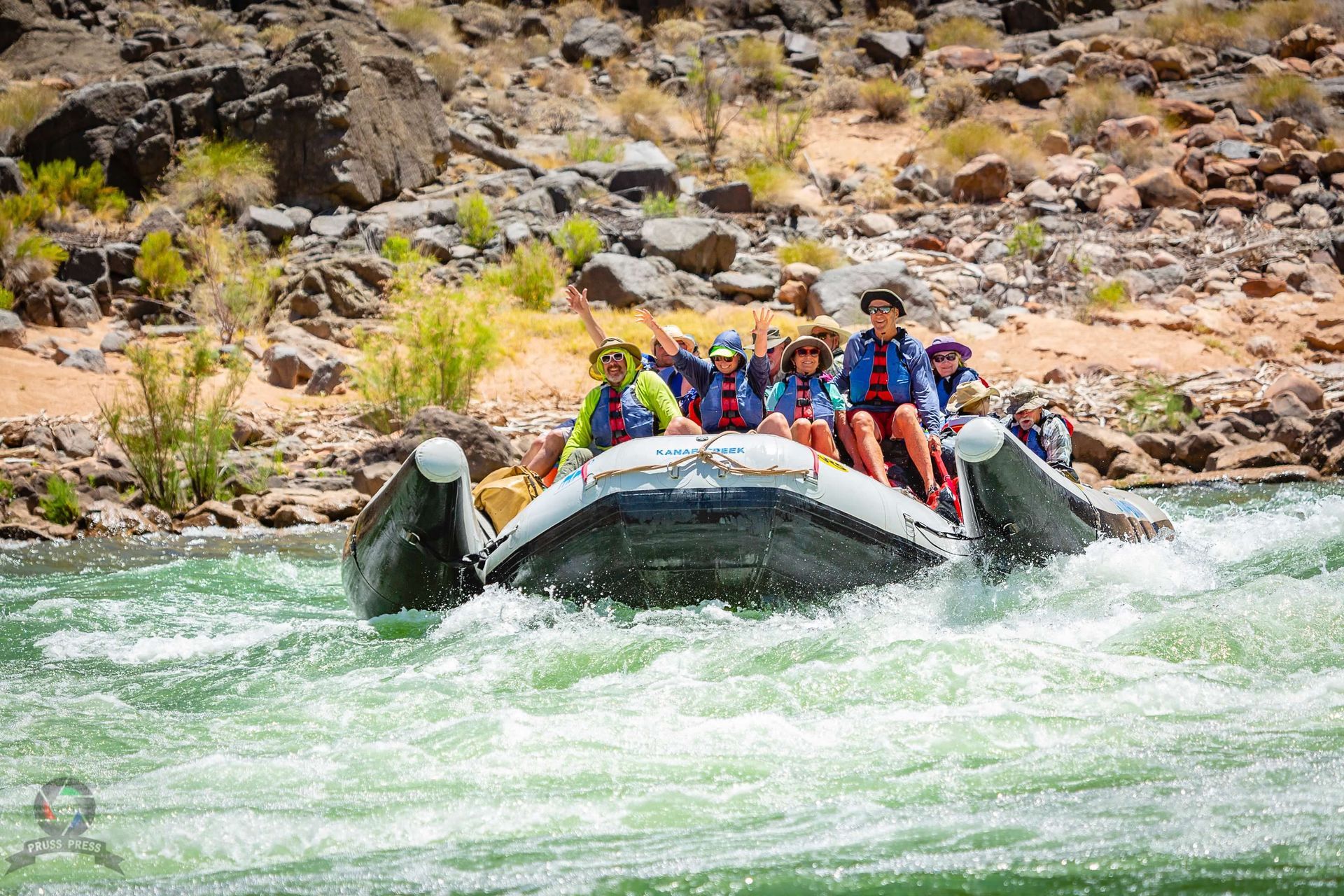 Group of people rafting down a river, navigating whitewater rapids.