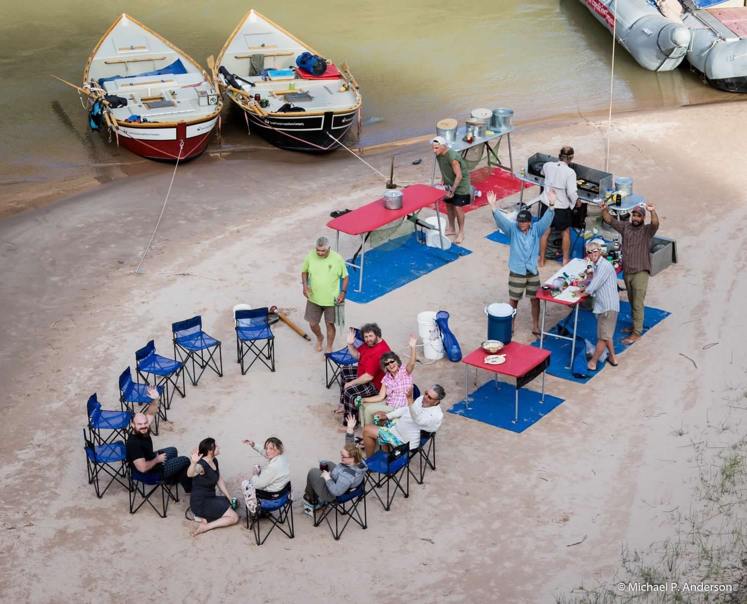 A group of people sitting around tables on a beach