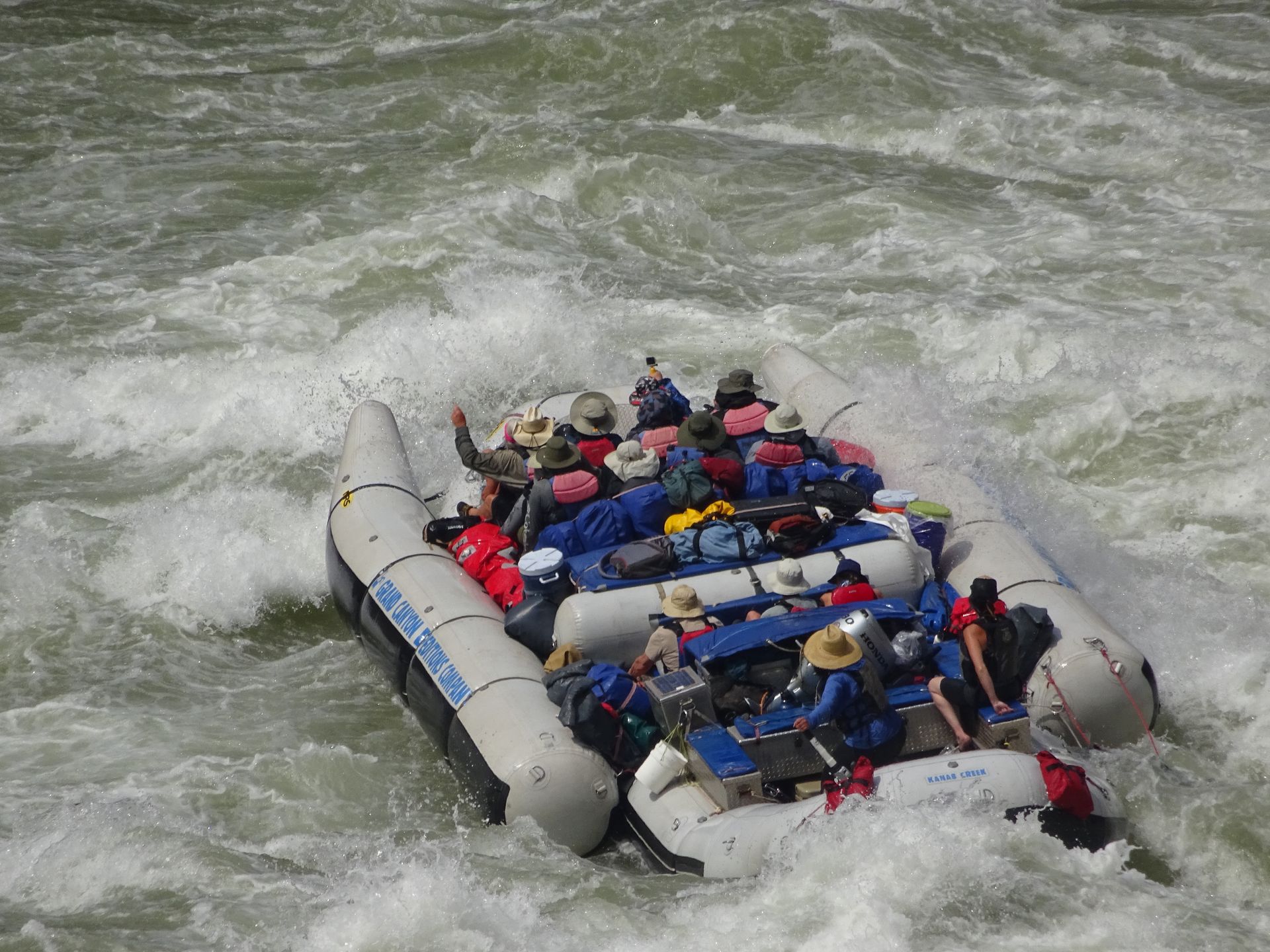 Raft with several people navigating whitewater rapids.