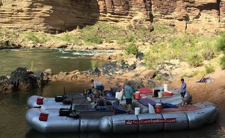 A group of rafts are docked on the shore of a river.