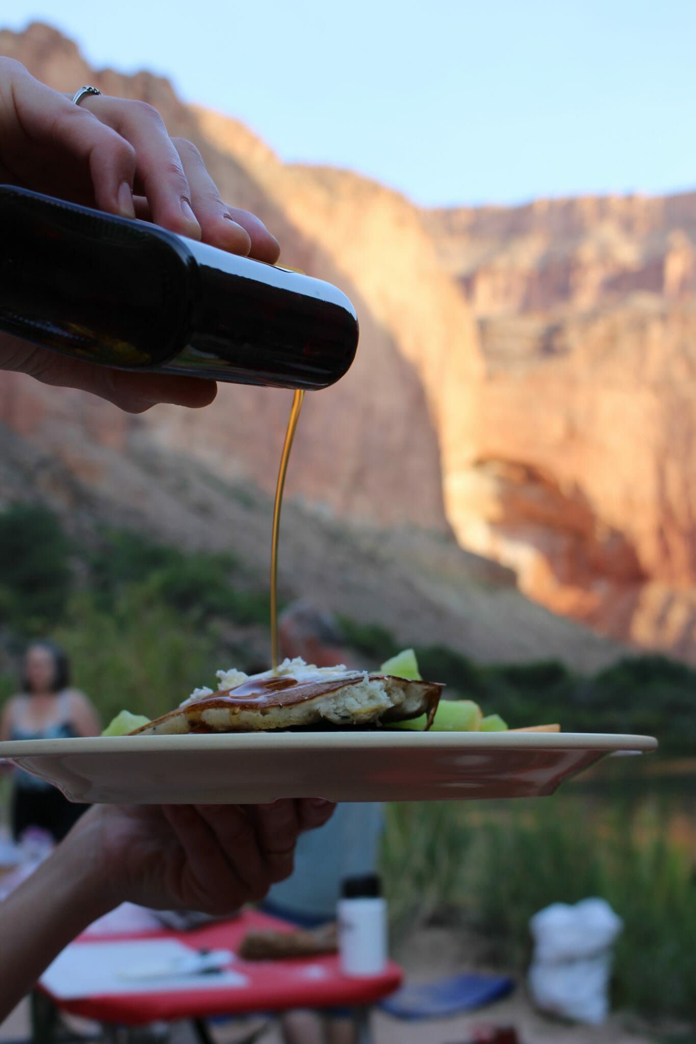 A person is pouring syrup on a plate of food