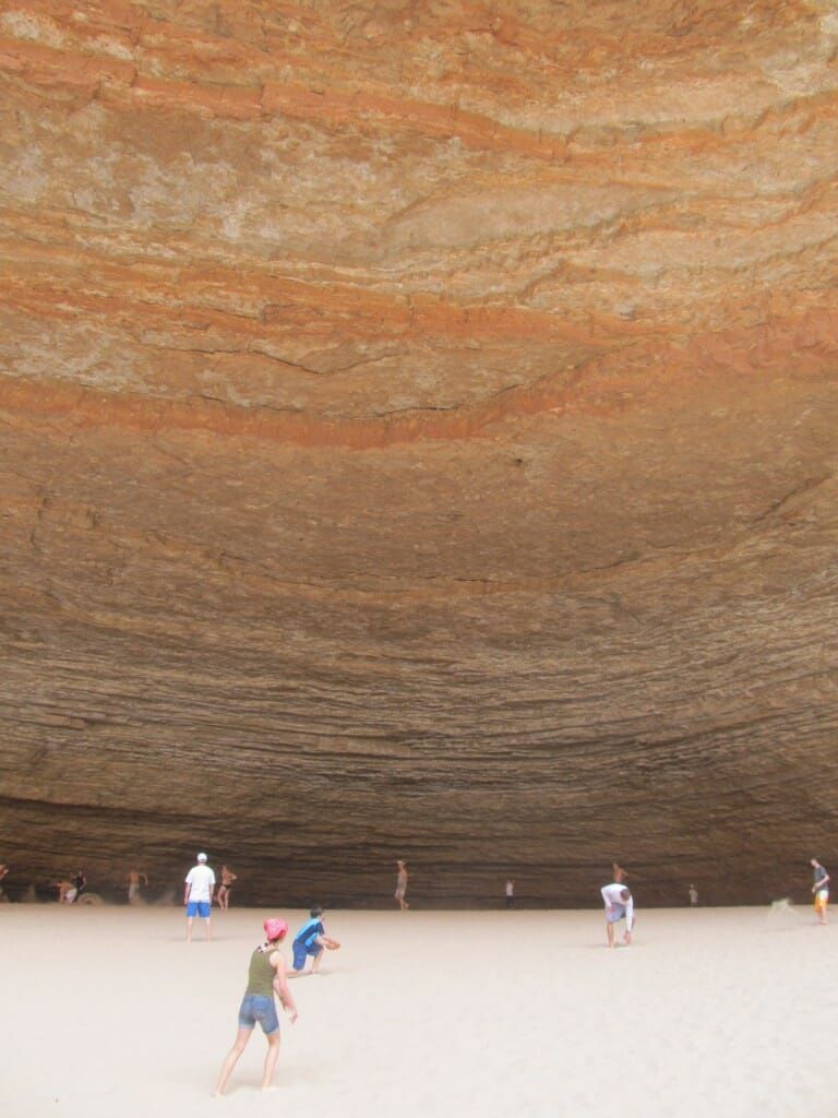 A group of people are standing in a cave looking up at the ceiling.