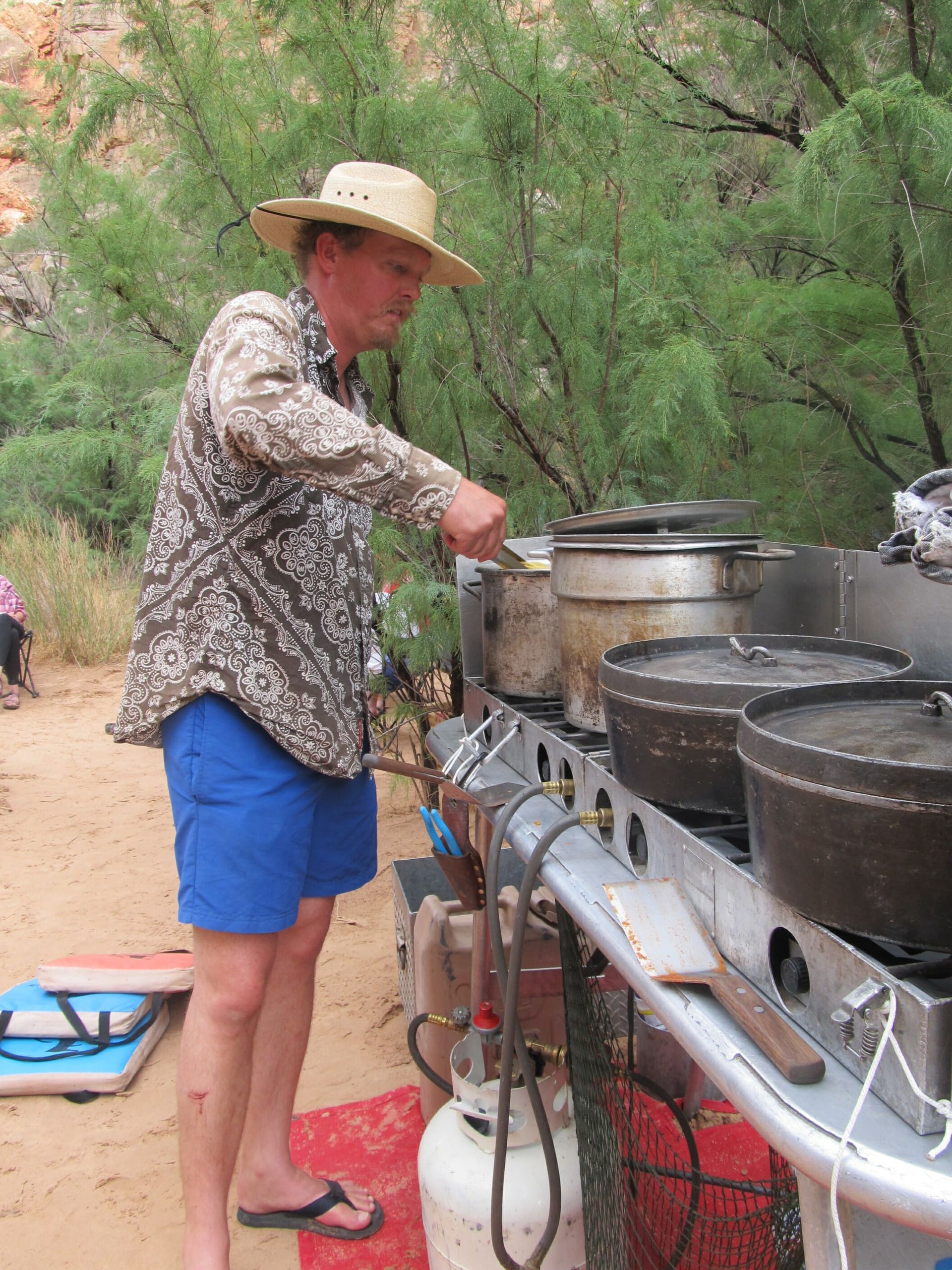 A man in a hat is preparing food on a grill