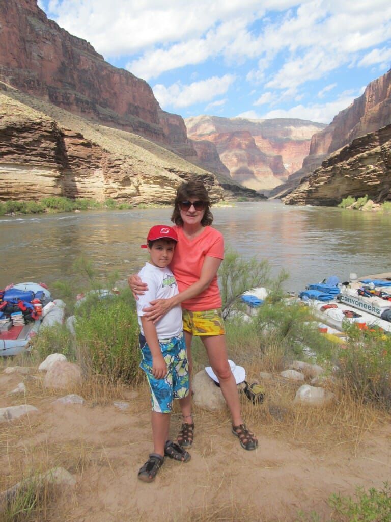 A woman and a boy are posing for a picture in front of a river.