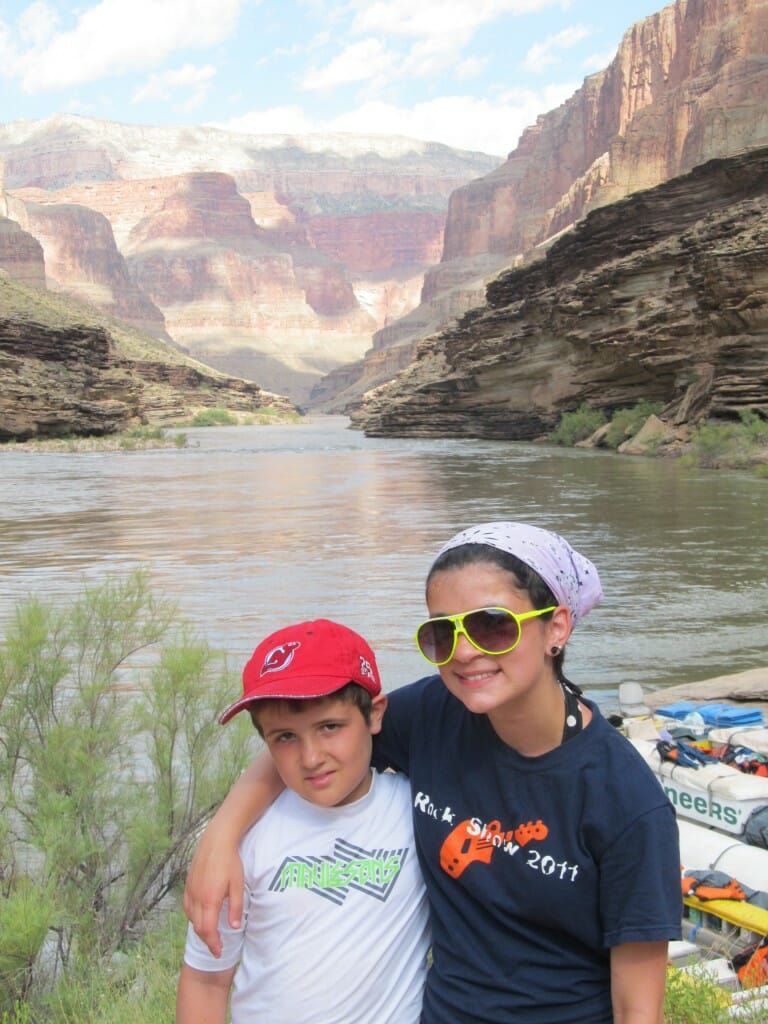 A boy and a girl are posing for a picture in front of a river