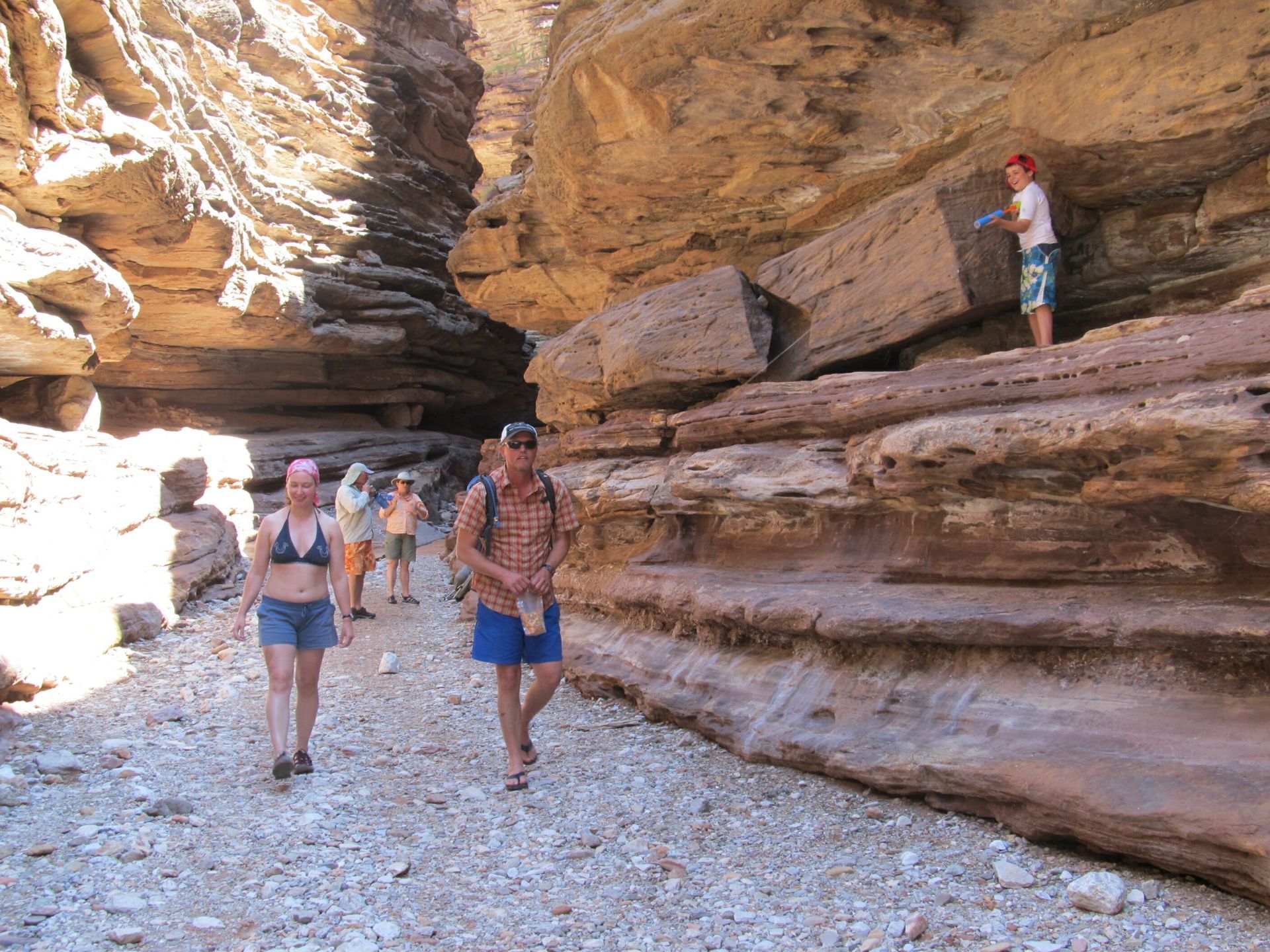 A group of people are walking through a canyon.