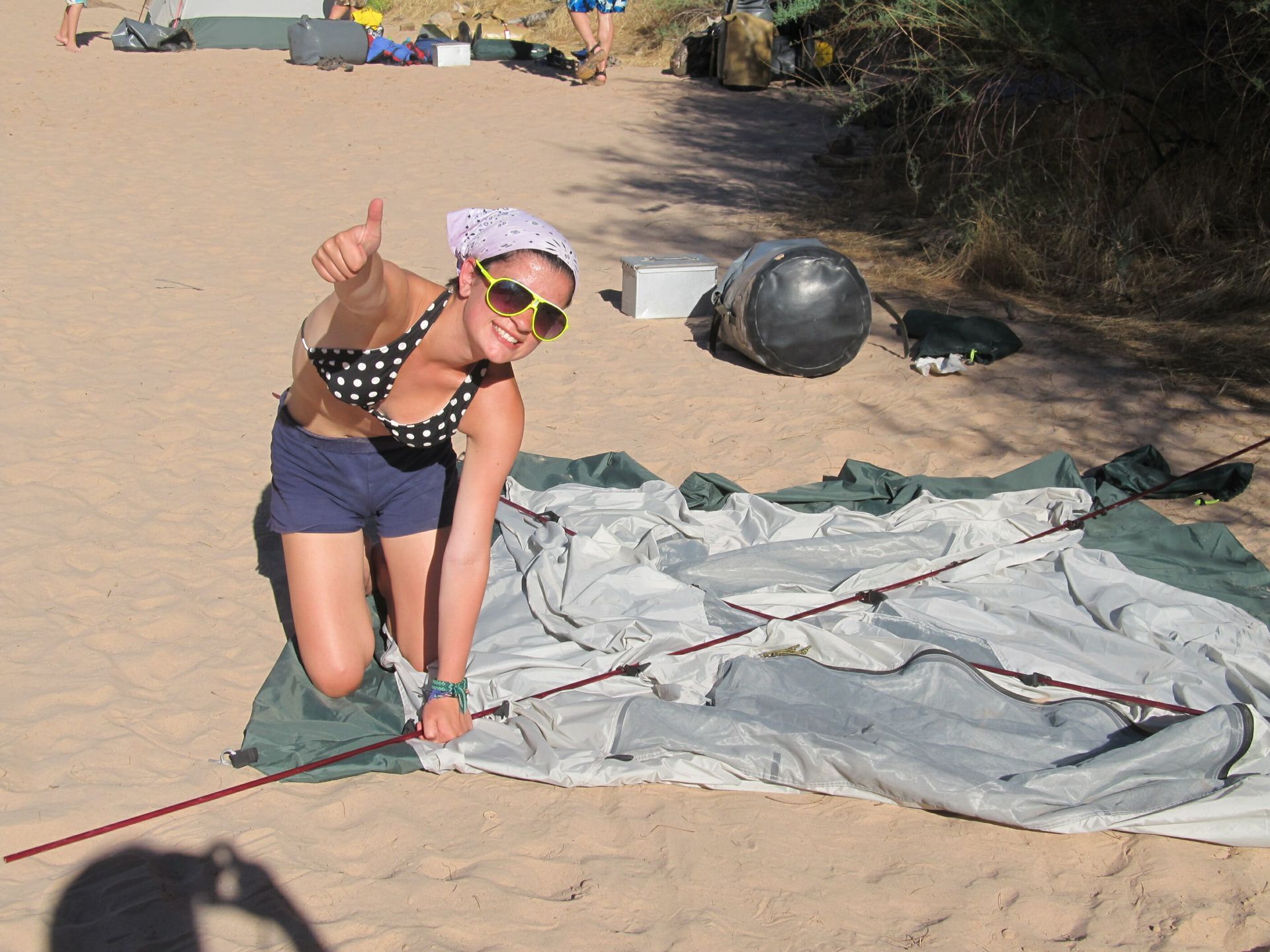 A woman in a bikini giving a thumbs up on the beach