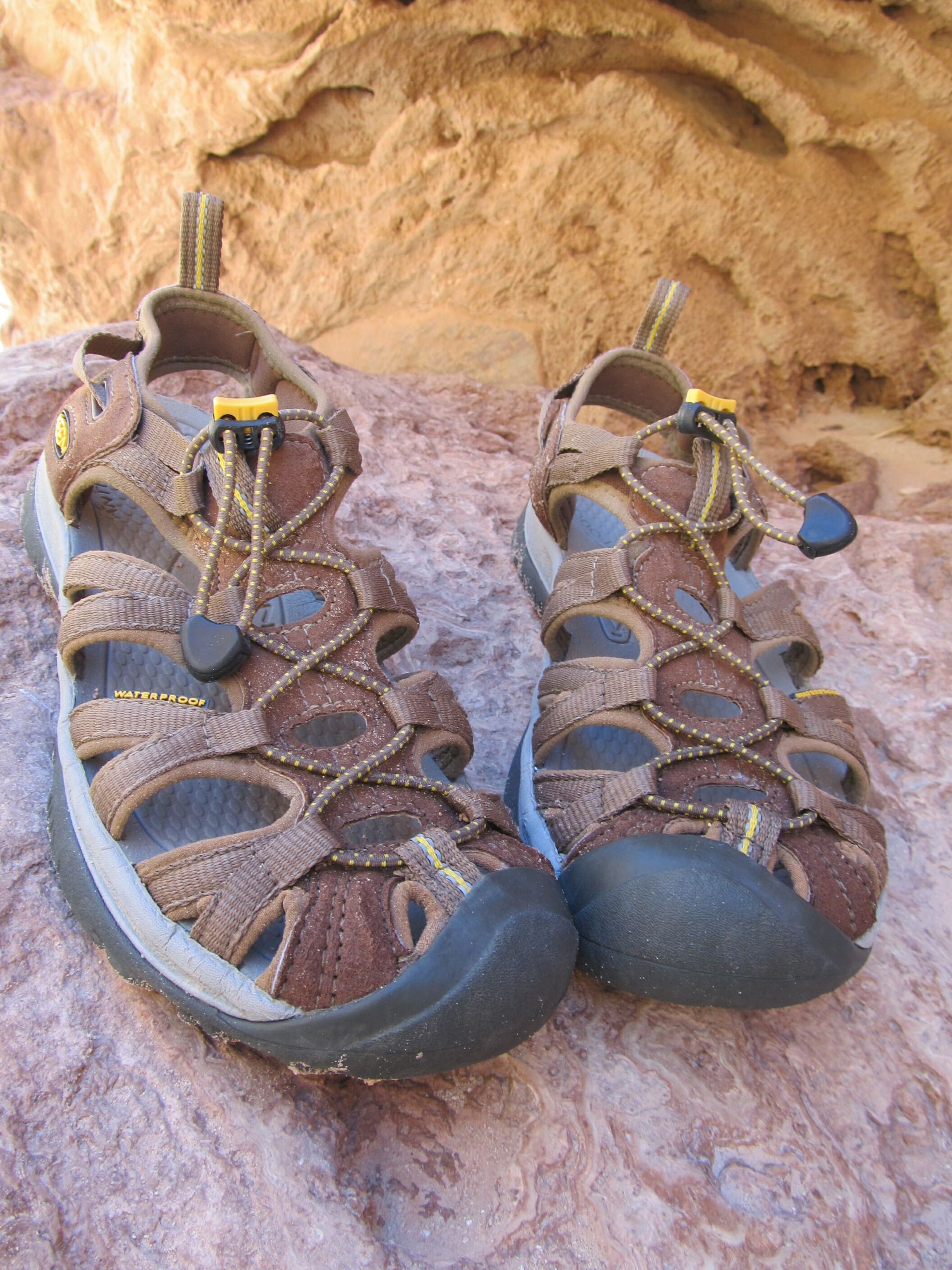 A pair of brown sandals are sitting on a rock