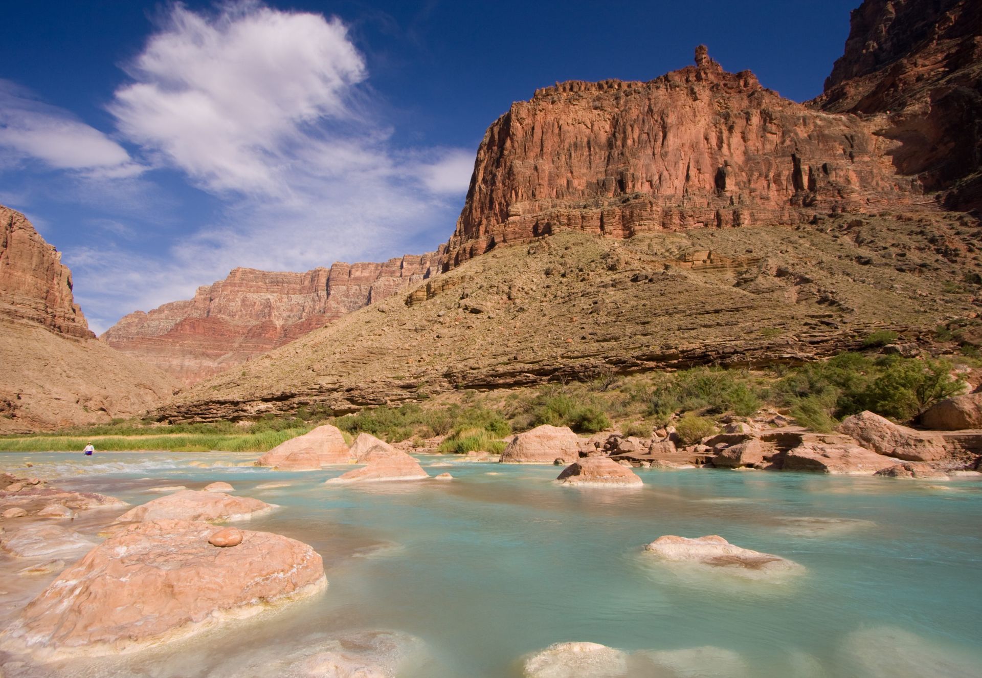 A river in the middle of a canyon with mountains in the background