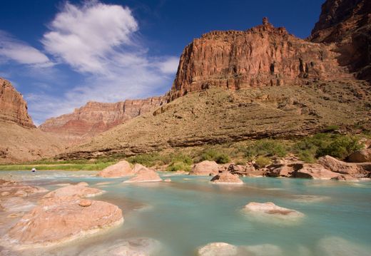 A river in the middle of a canyon with mountains in the background