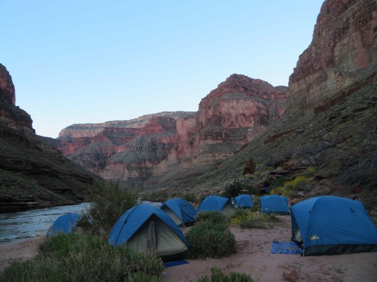 A group of tents are set up in the middle of a canyon
