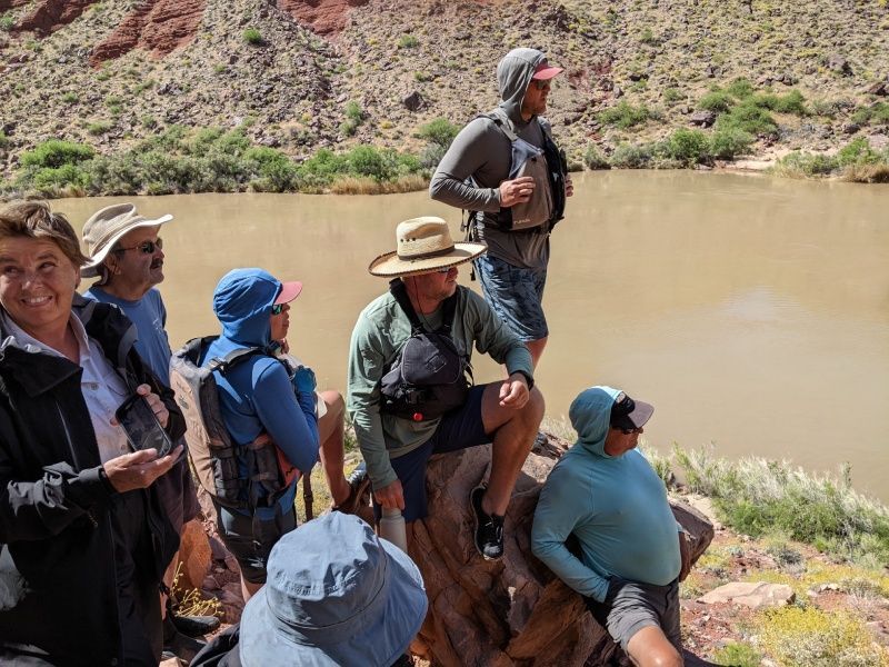 A group of people are sitting on a rock near a river.
