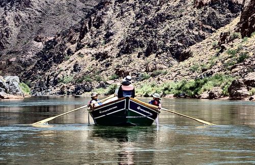 A man is rowing a boat down a river.