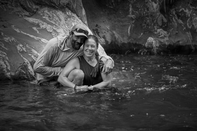 A man and a woman are posing for a picture in the water.